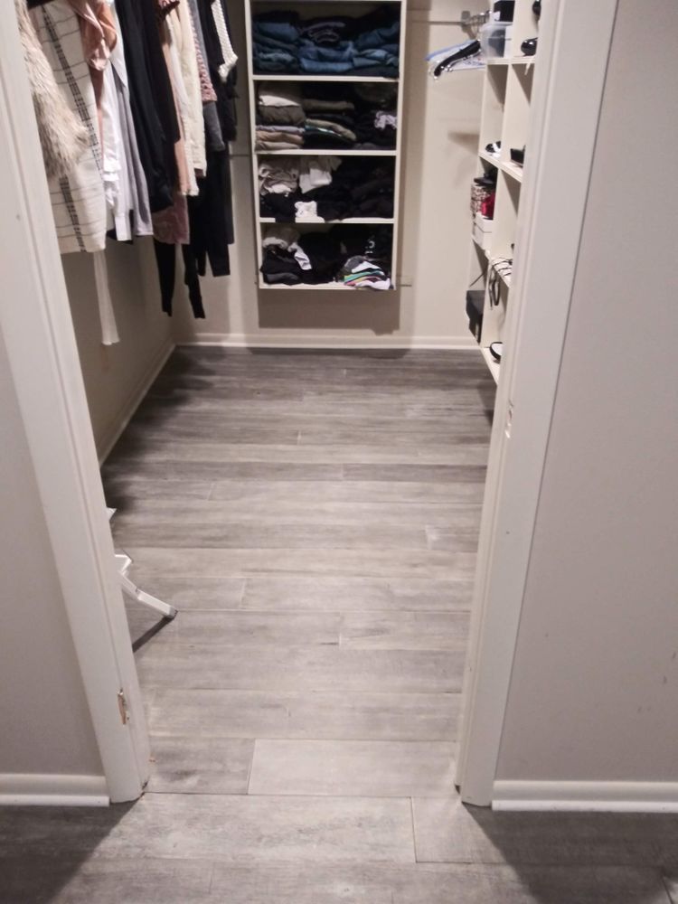 A walk in closet with a wooden floor and shelves filled with clothes