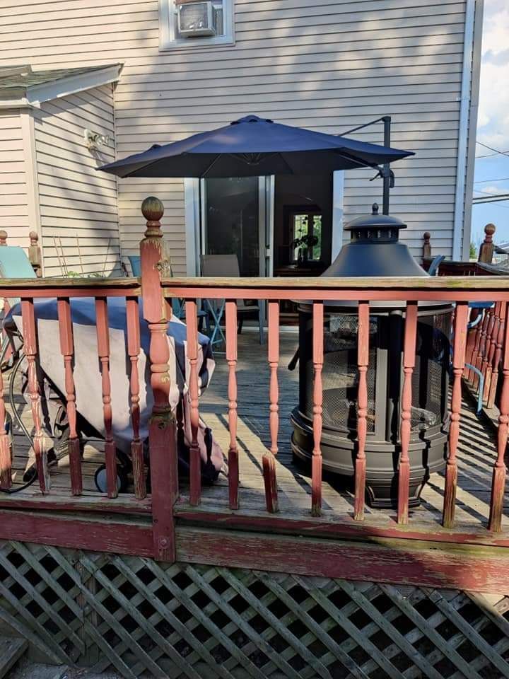 A deck with a blue umbrella and a heater on it