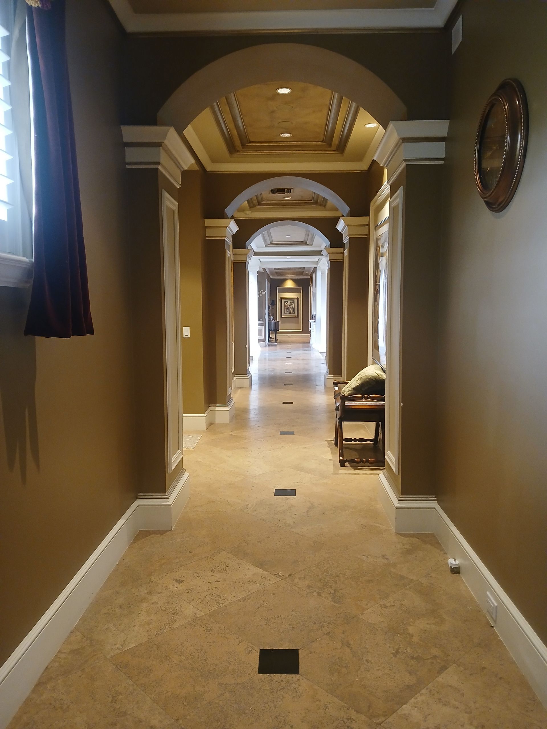 A long hallway with arches and a clock on the wall