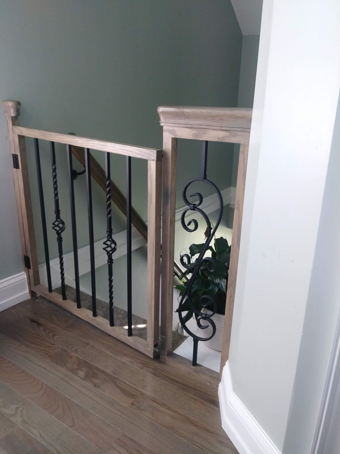 A staircase with a wooden gate and a wrought iron railing