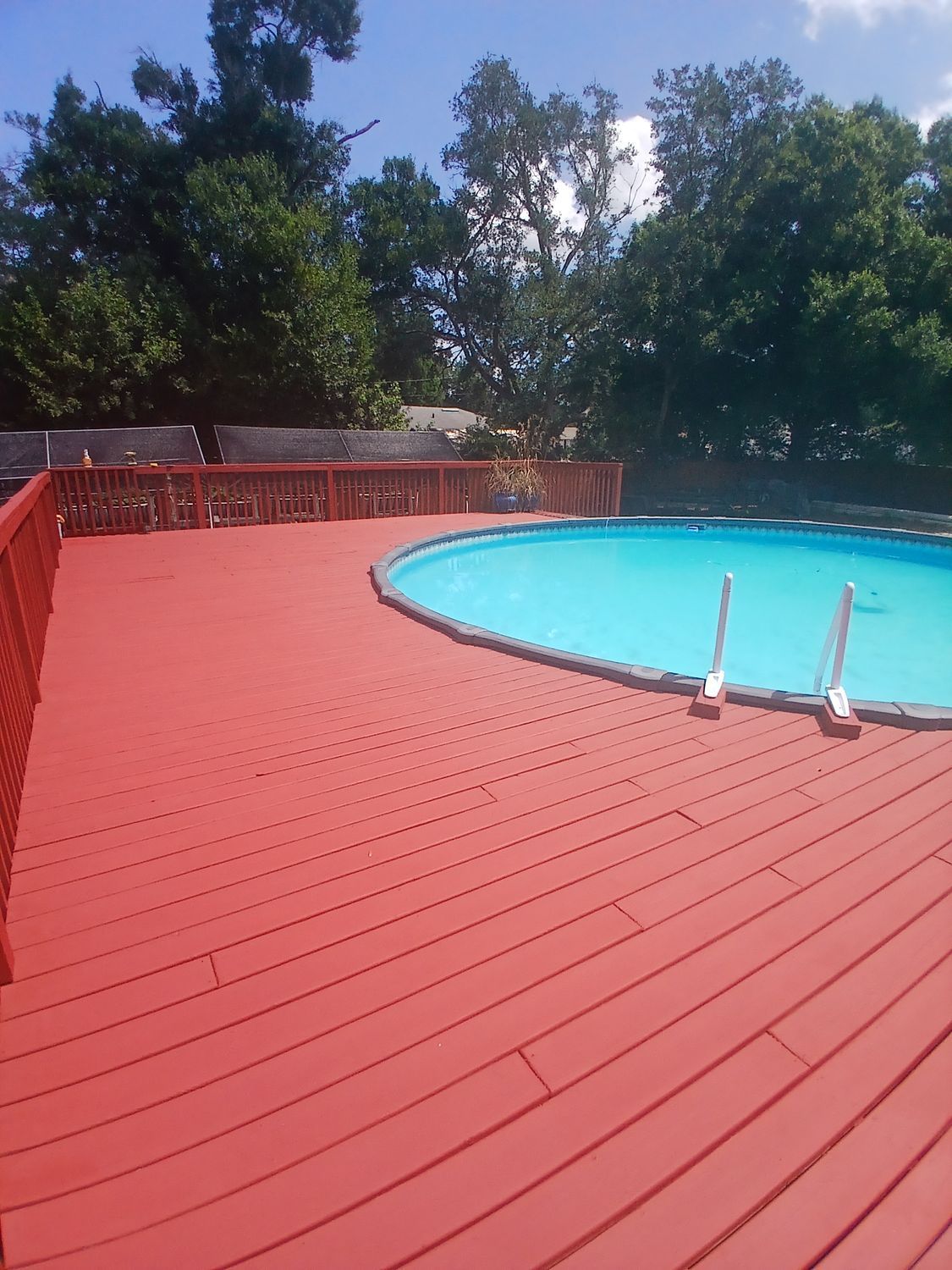 A red deck with a swimming pool in the background