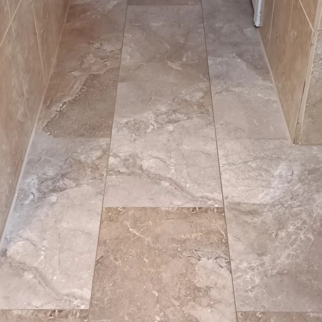 A tiled floor in a bathroom next to a washing machine