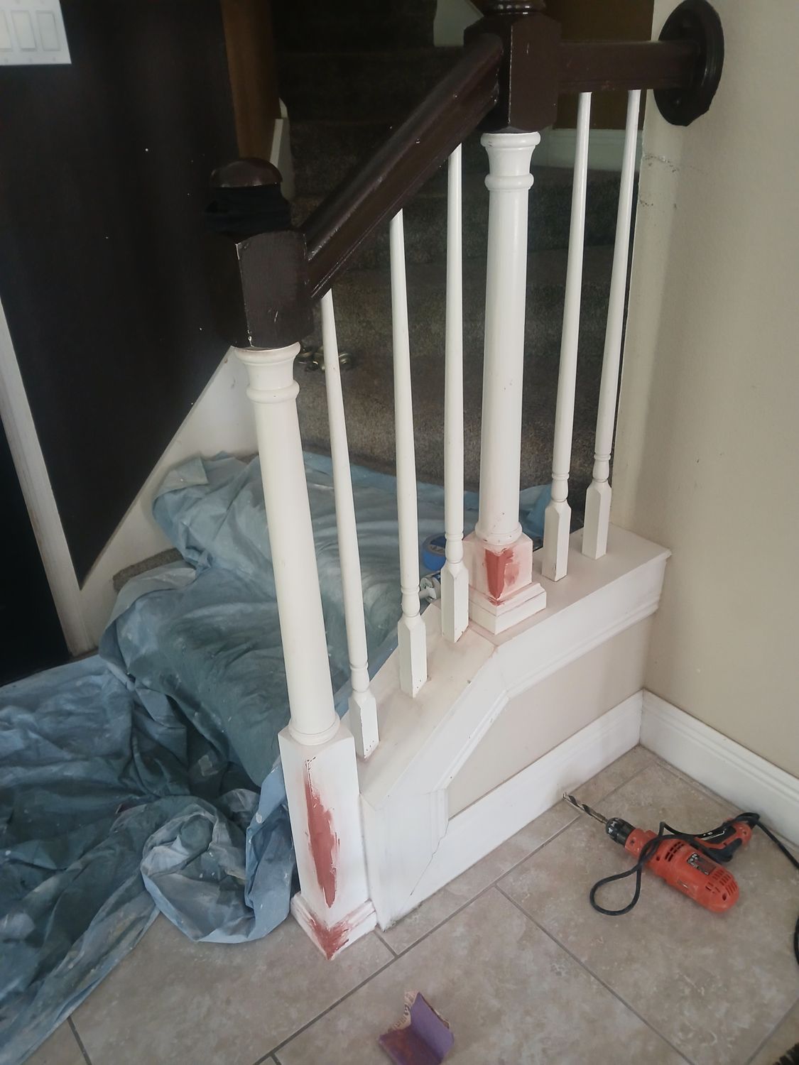 A staircase with white railings and a drill on the floor