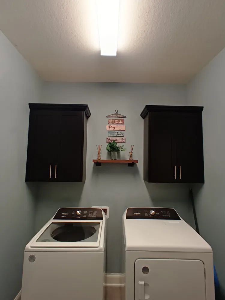 A laundry room with two washing machines and a dryer