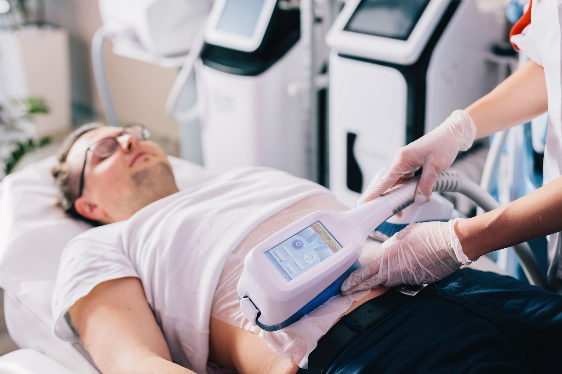 A man is laying on a bed with a machine on his stomach.