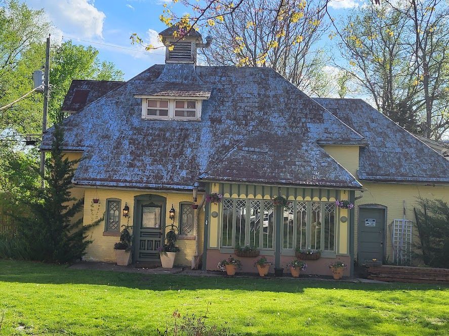 A large house with a slate roof is sitting in the middle of a lush green field.