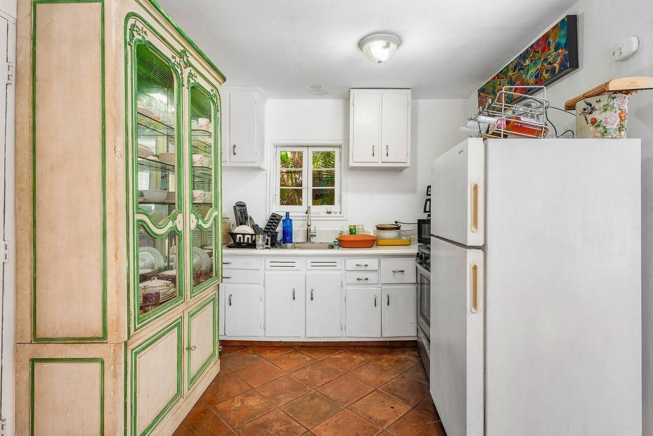 A kitchen with white cabinets , a refrigerator , a stove , and a hutch.