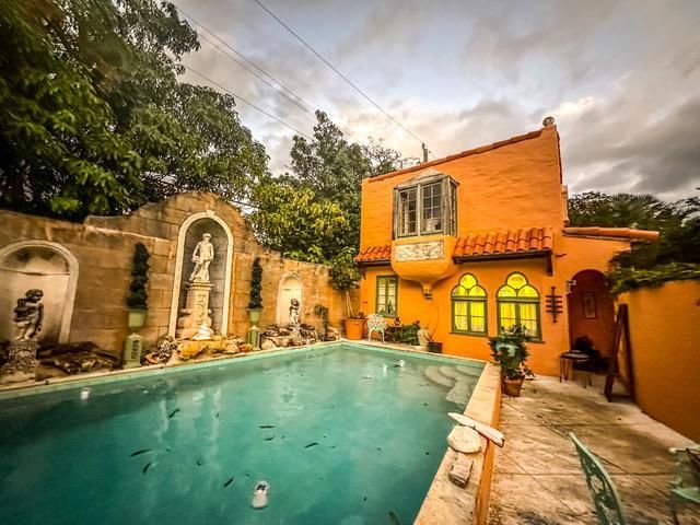 A large orange house with a swimming pool in front of it