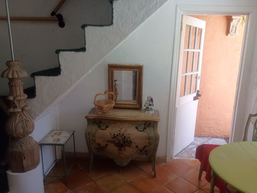 A room with stairs , a dresser , a mirror and a table.