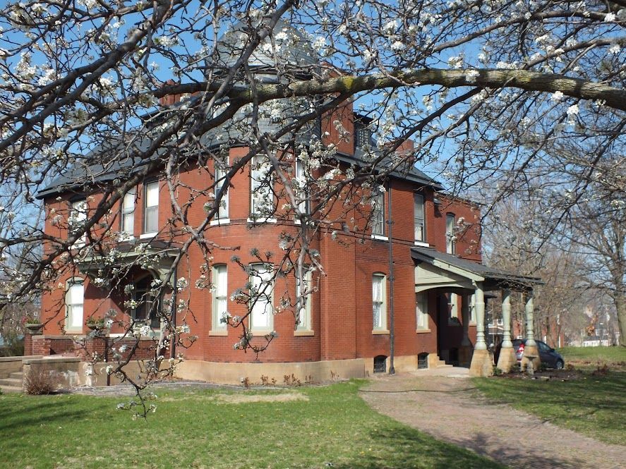 A large red brick house with trees in front of it
