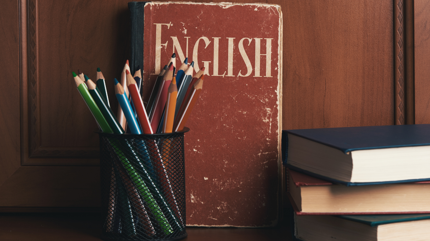 Stack of books, pencils, and an English textbook on a wooden surface.