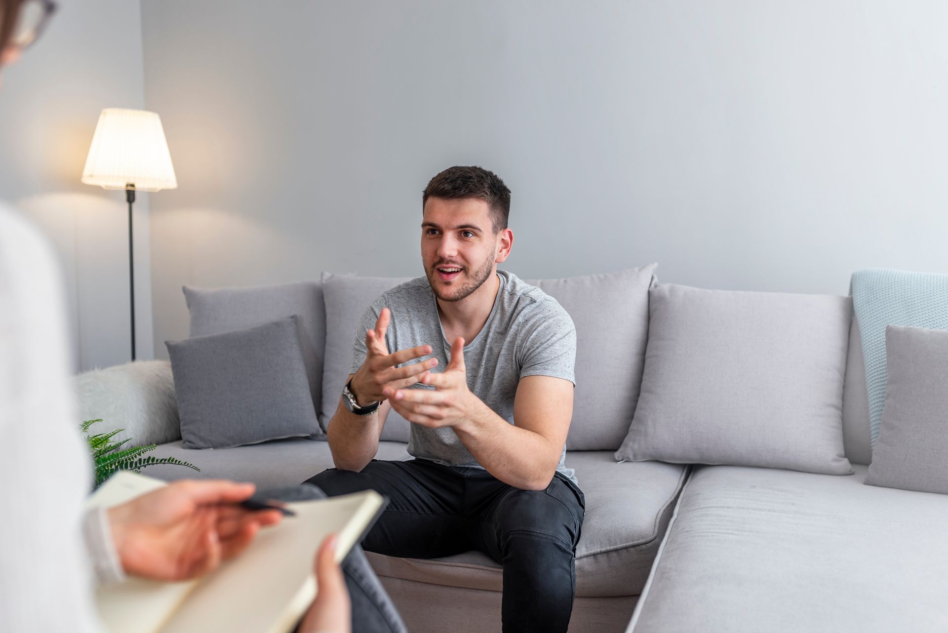 A man is sitting on a couch talking to a woman.