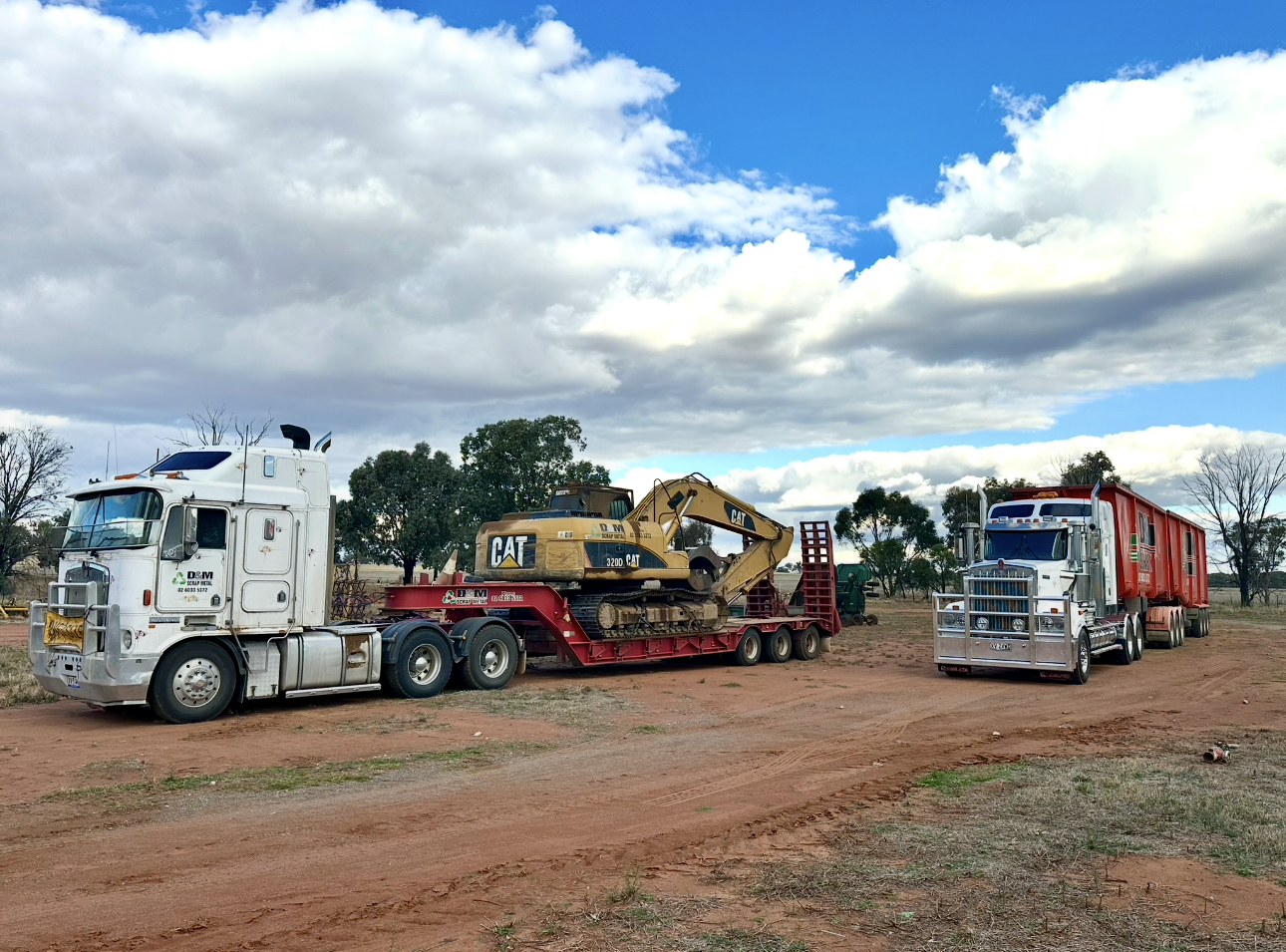 A white truck with a red trailer with a yellow excavator.