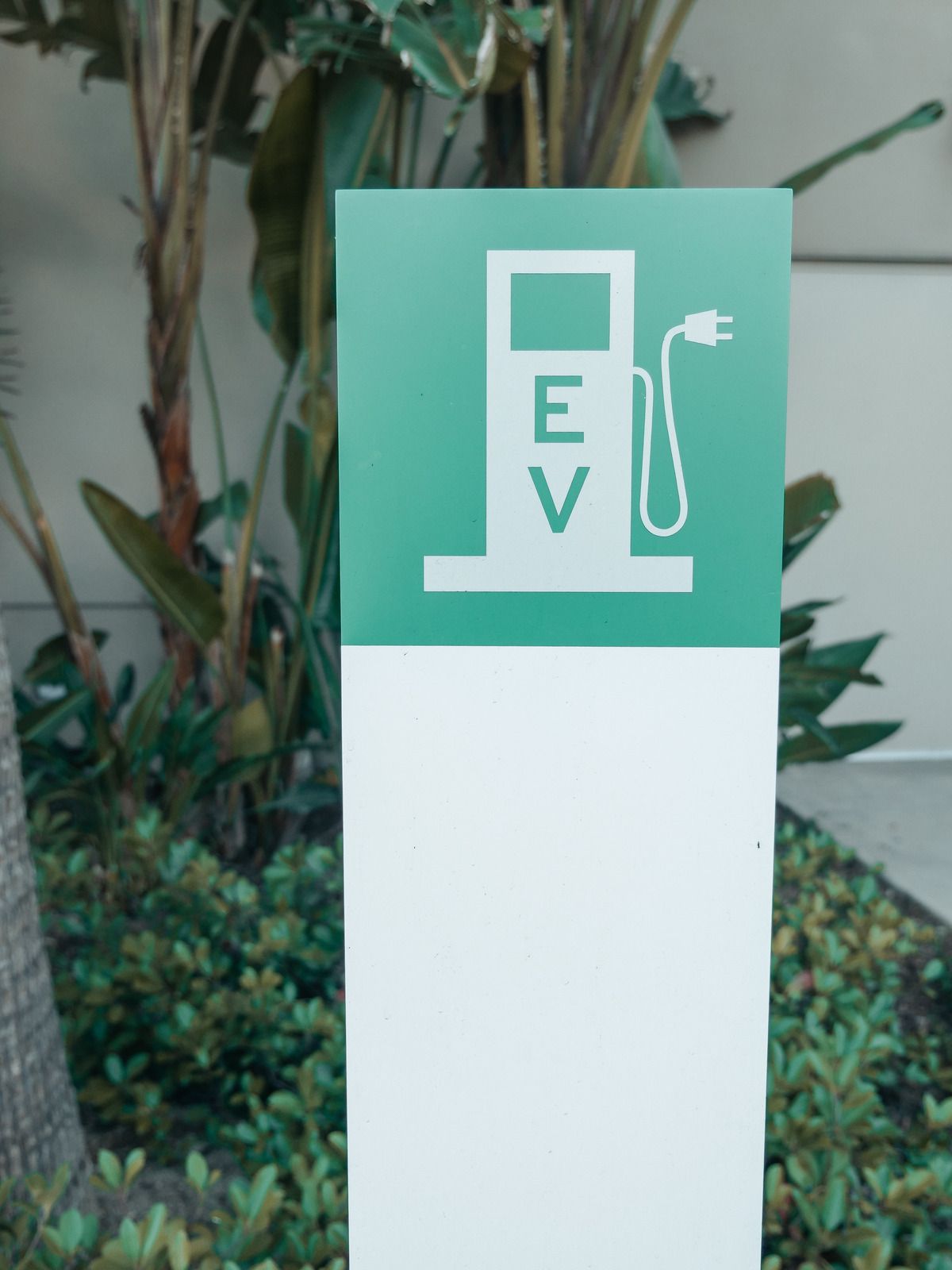 Green and white sign for electric vehicle charging station, with a plug icon.