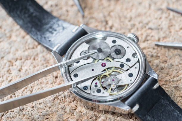 Close-up of watch restoration process with expert tools and clock repair supplies in use.