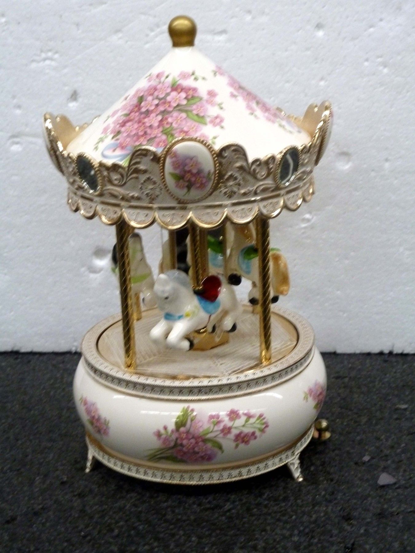 Carousel music box with floral decorations and horses.