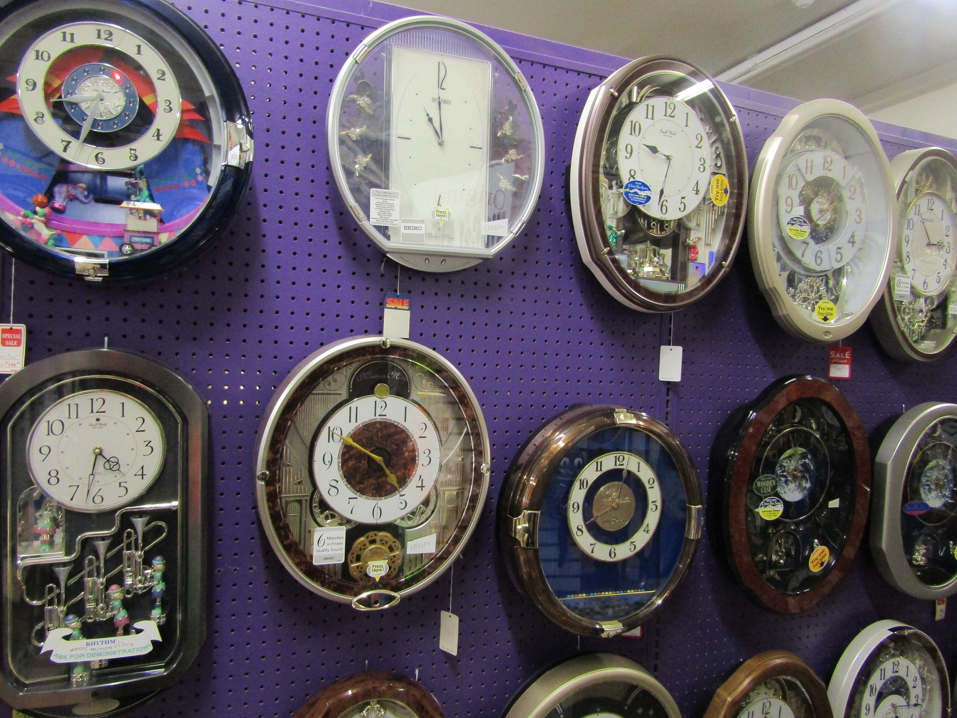 A bunch of clocks hanging on a purple wall