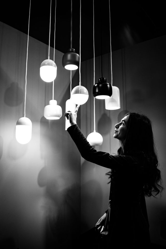 Person reaching toward hanging pendant lights in a dimly lit room