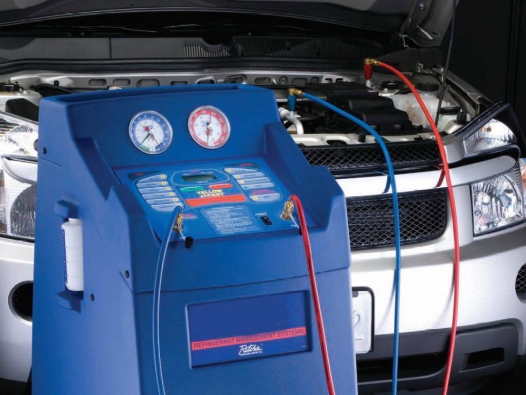 A car is being serviced with a machine in front of it - AK Auto Repair