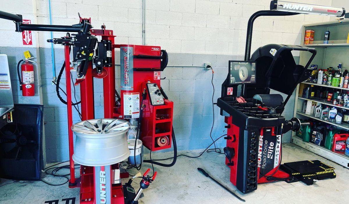 A tire changer is sitting next to a wheel balancer in a garage - AK Auto Repair