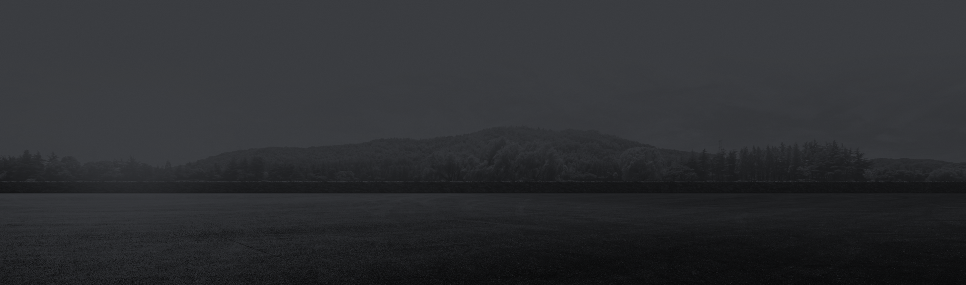 A black and white photo of a lake with trees in the background. | AK Auto Repair