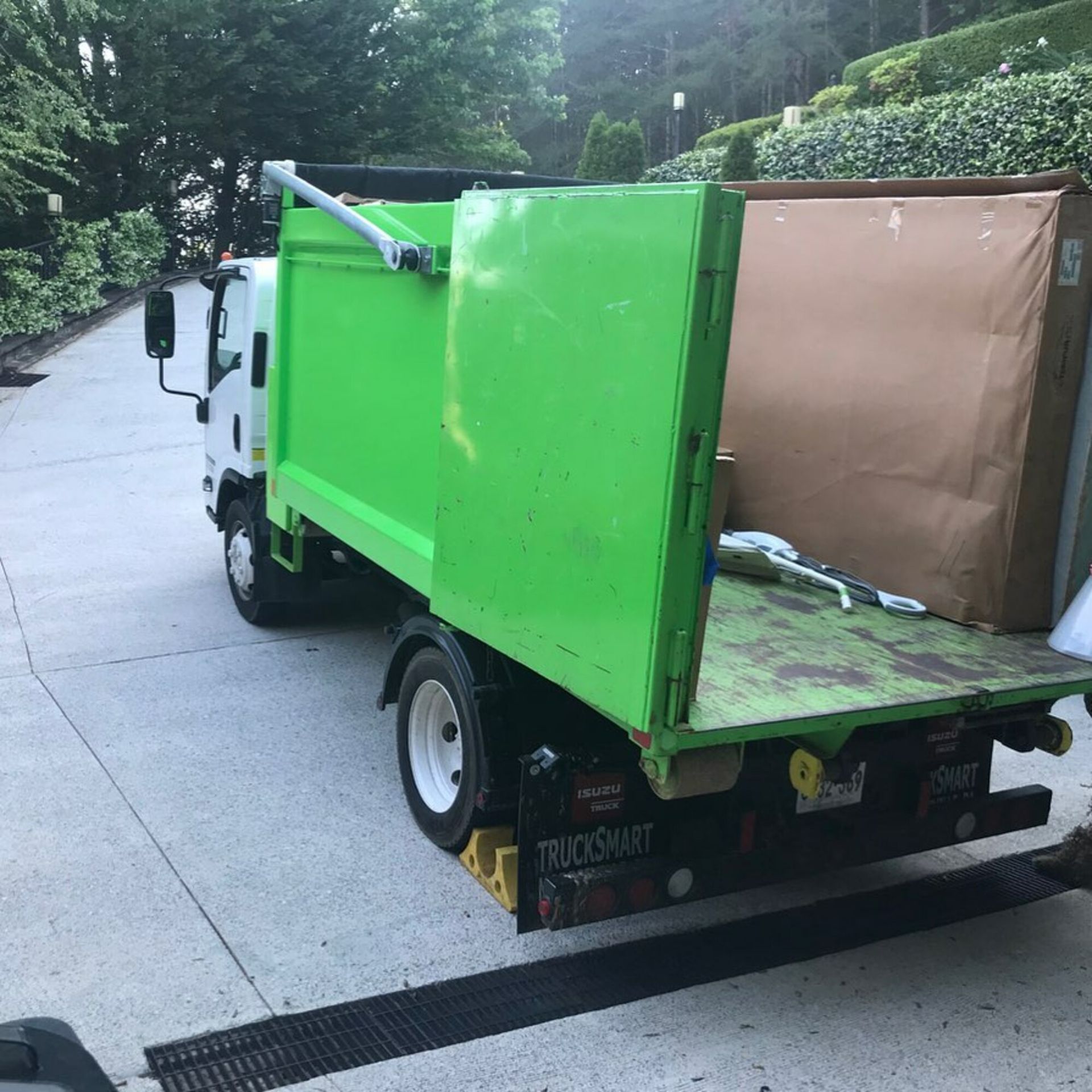 A green garbage truck is parked on the side of the road.