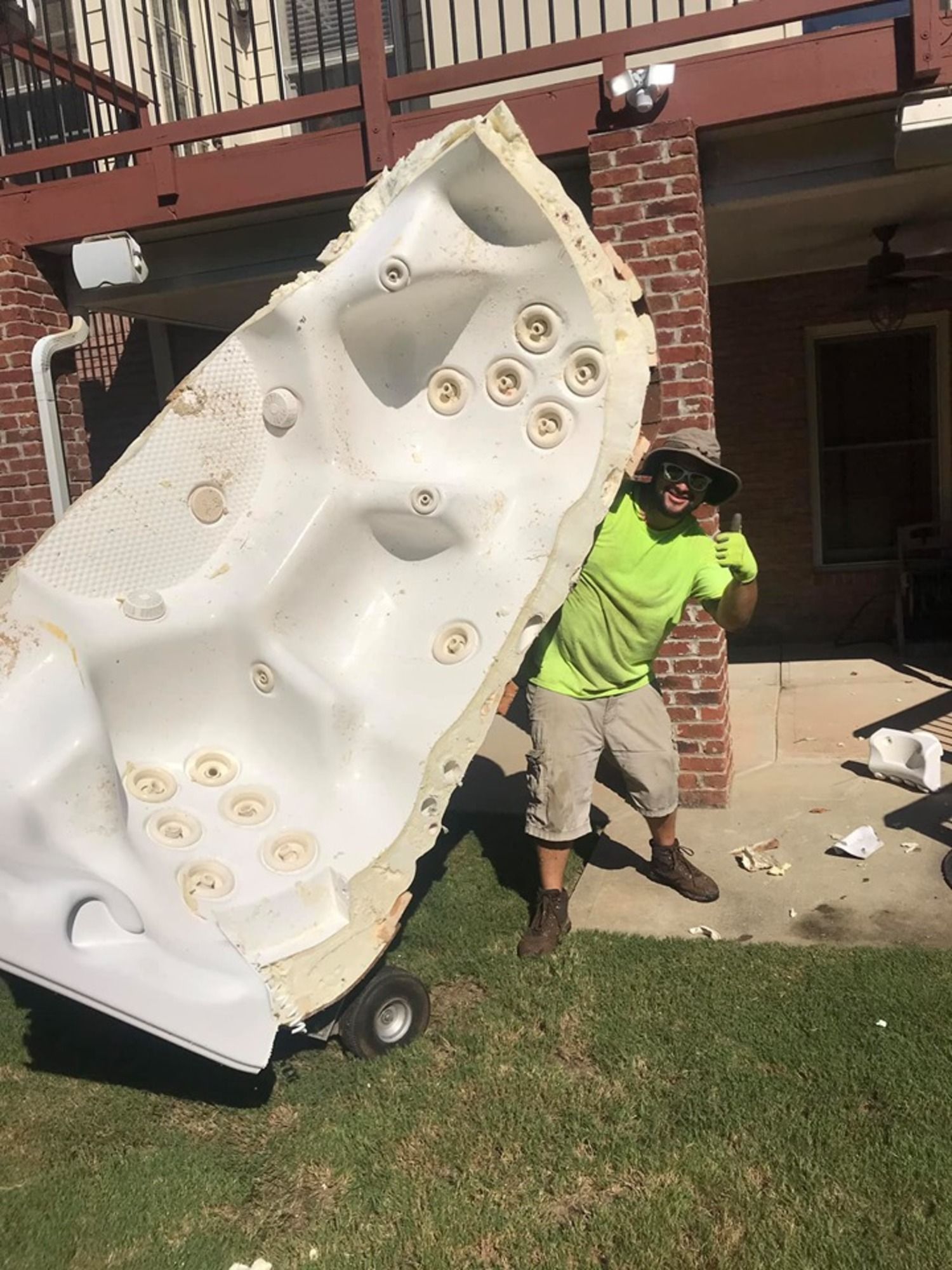 A man is carrying a large hot tub on a cart.