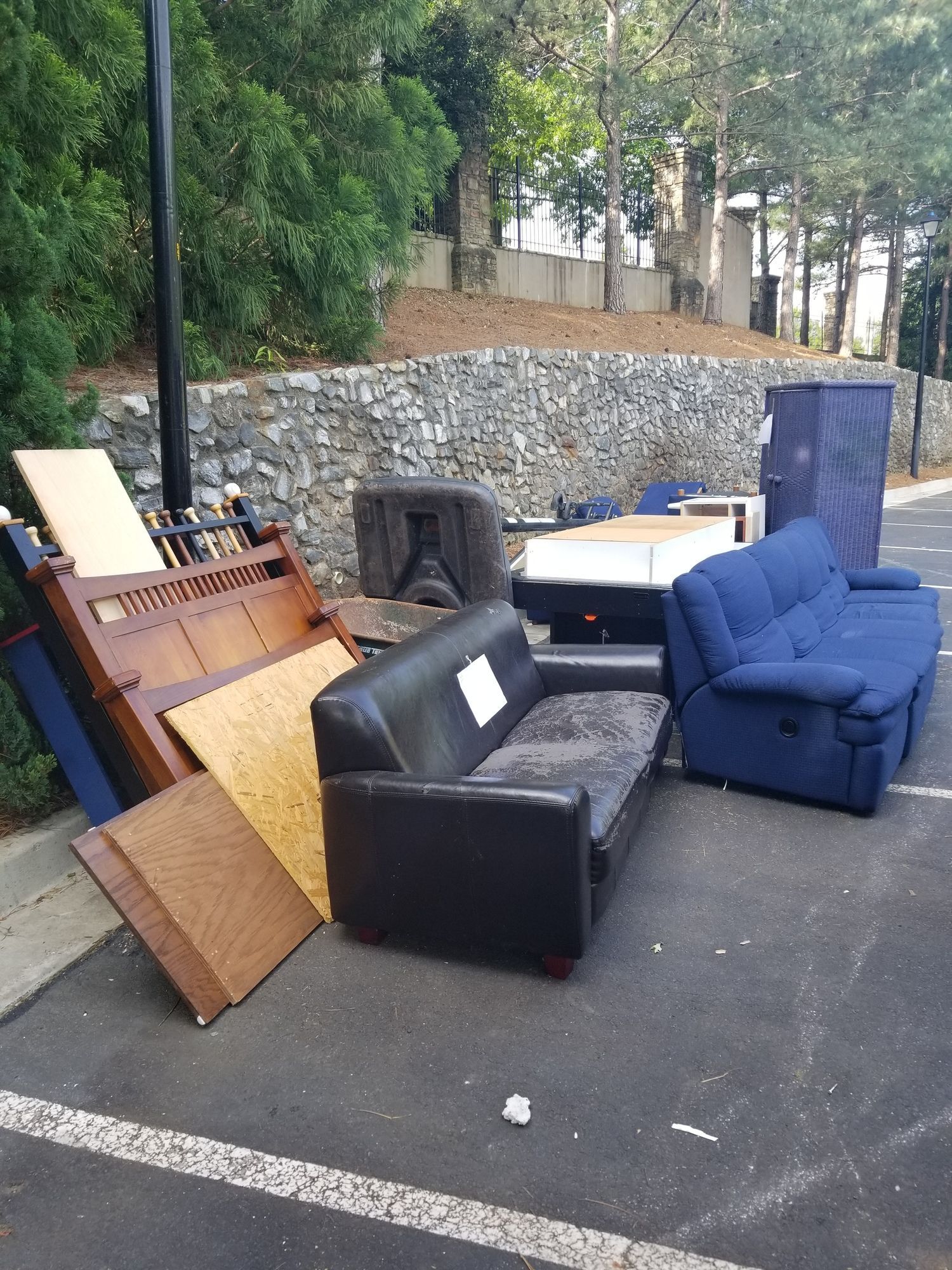 A bunch of furniture is sitting on the ground in a parking lot.