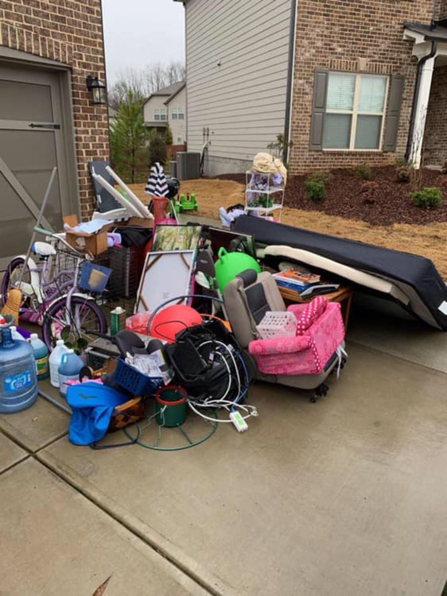 A pile of junk is sitting on the sidewalk in front of a house.