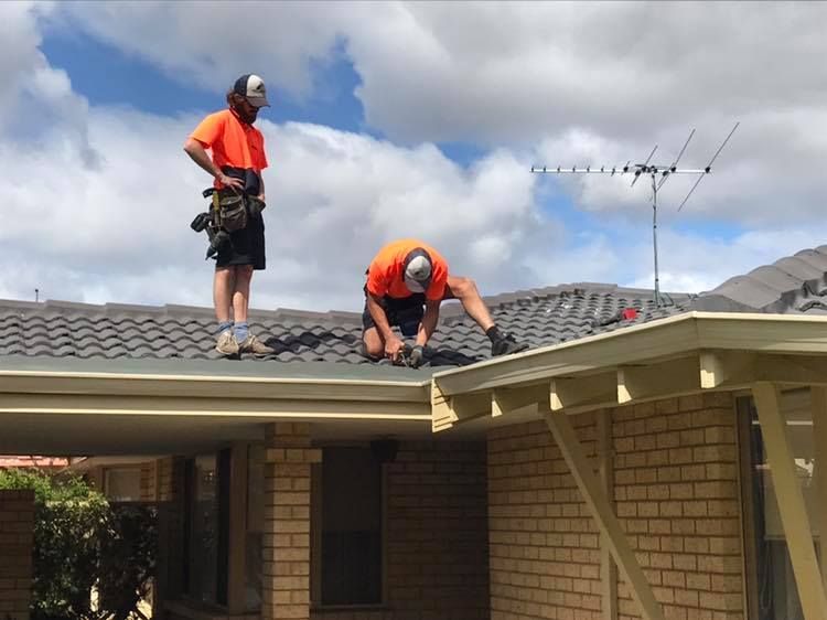 Two men are working on the roof of a house