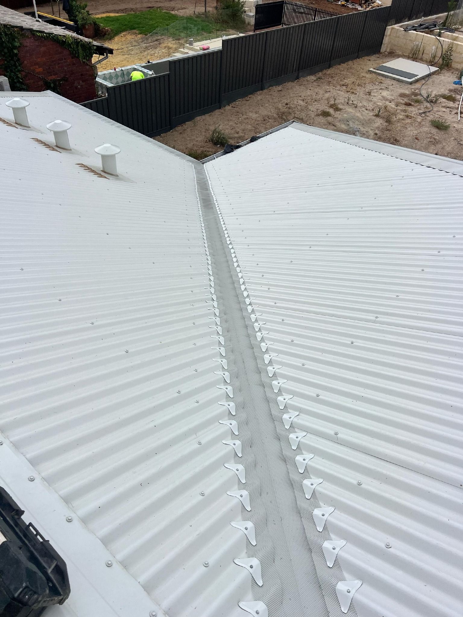 A white roof with a drain on the side of it.