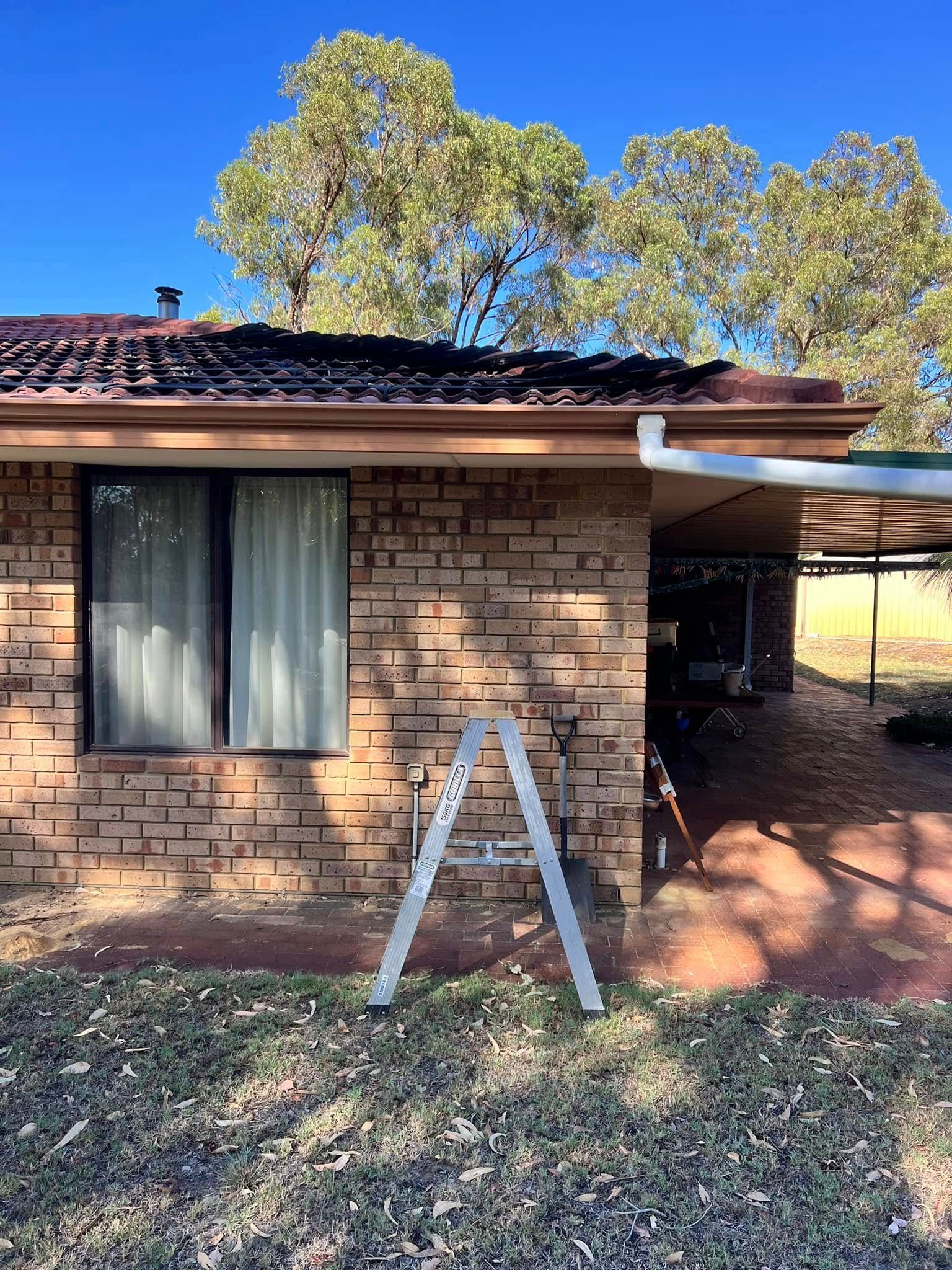 A ladder is sitting in front of a brick house.