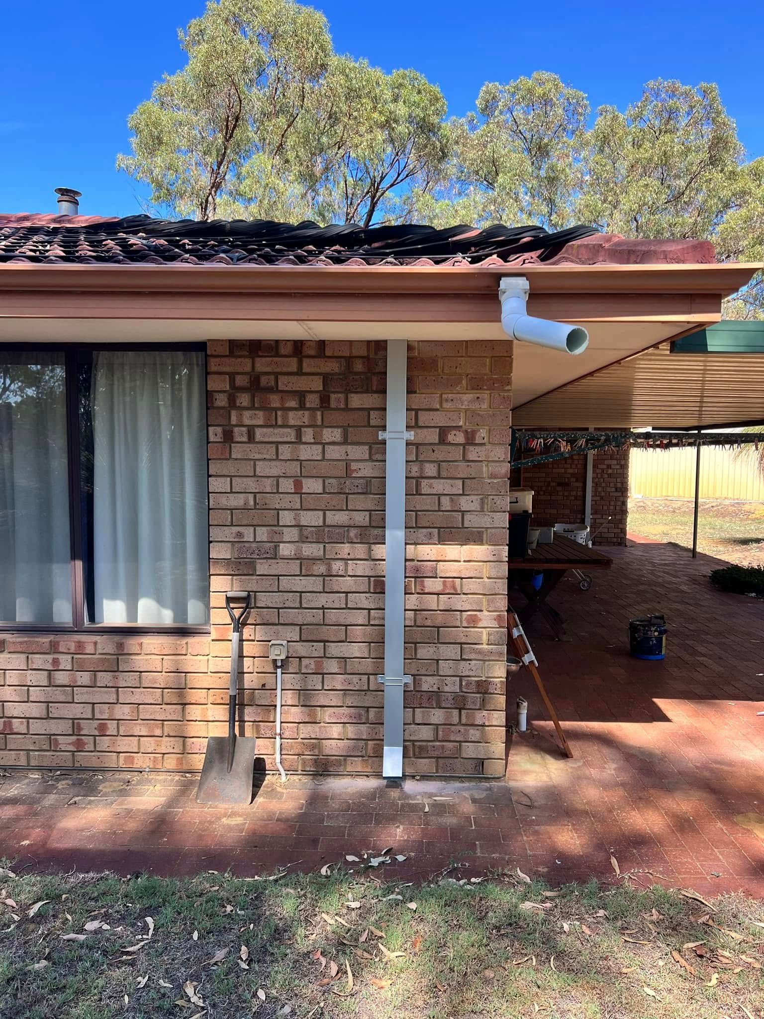 A person wearing gloves is cleaning a gutter on a roof.