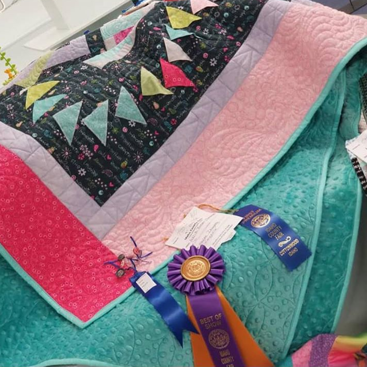 A quilt with a ribbon that says best of show