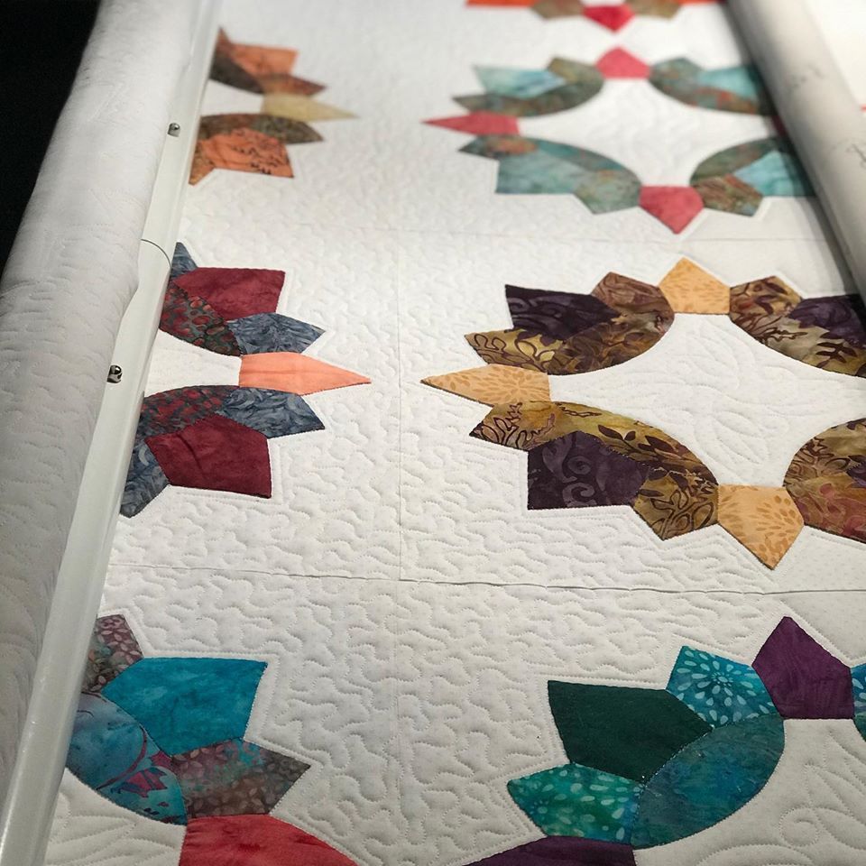A colorful quilt is being made on a machine