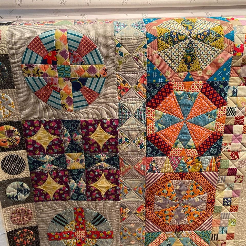 A colorful quilt is hanging on a wall.