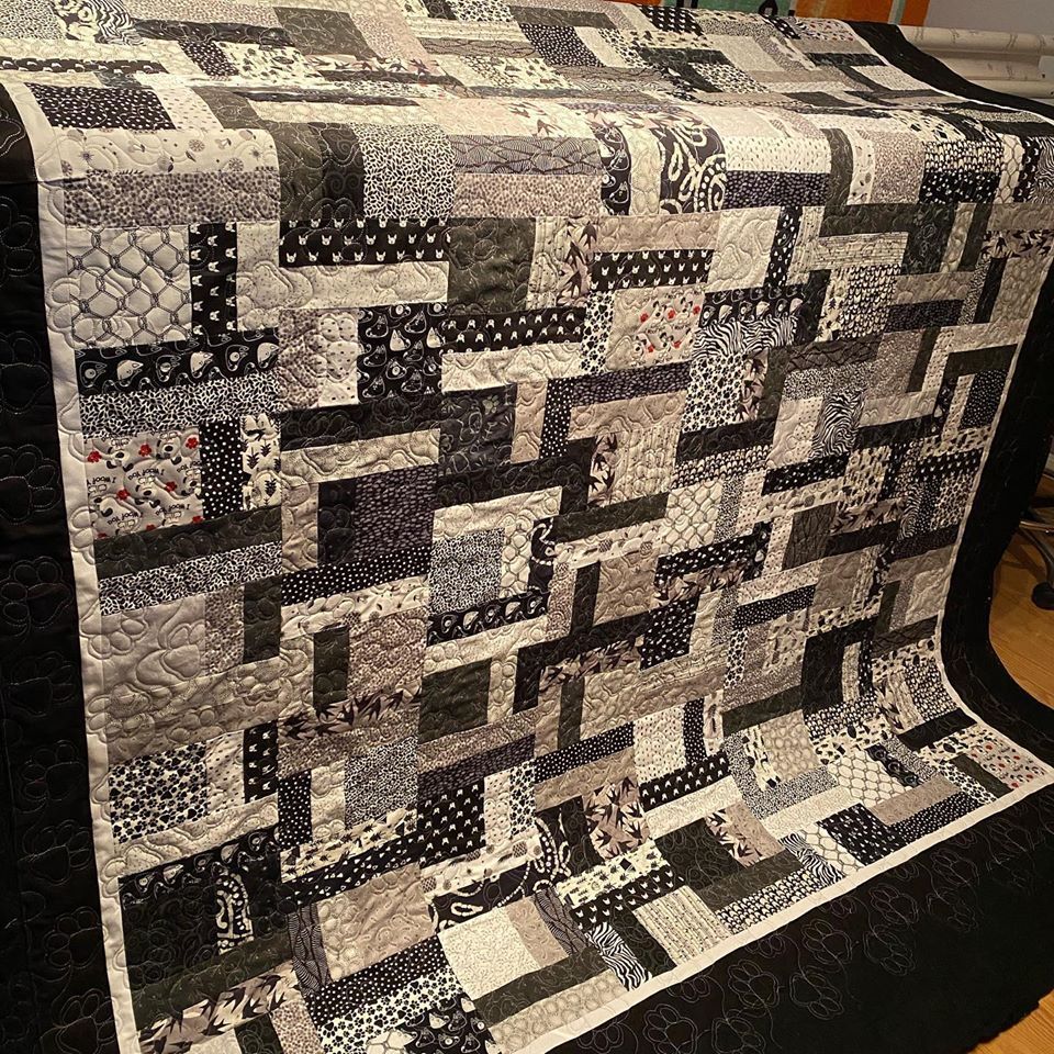 A black and white quilt is sitting on a wooden table.