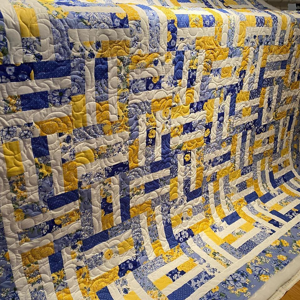 A blue and yellow quilt is sitting on a wooden table.