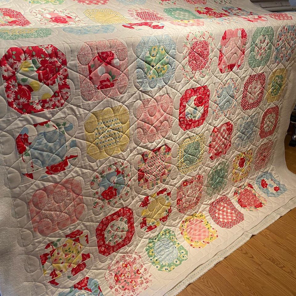 A colorful quilt is sitting on a wooden floor.