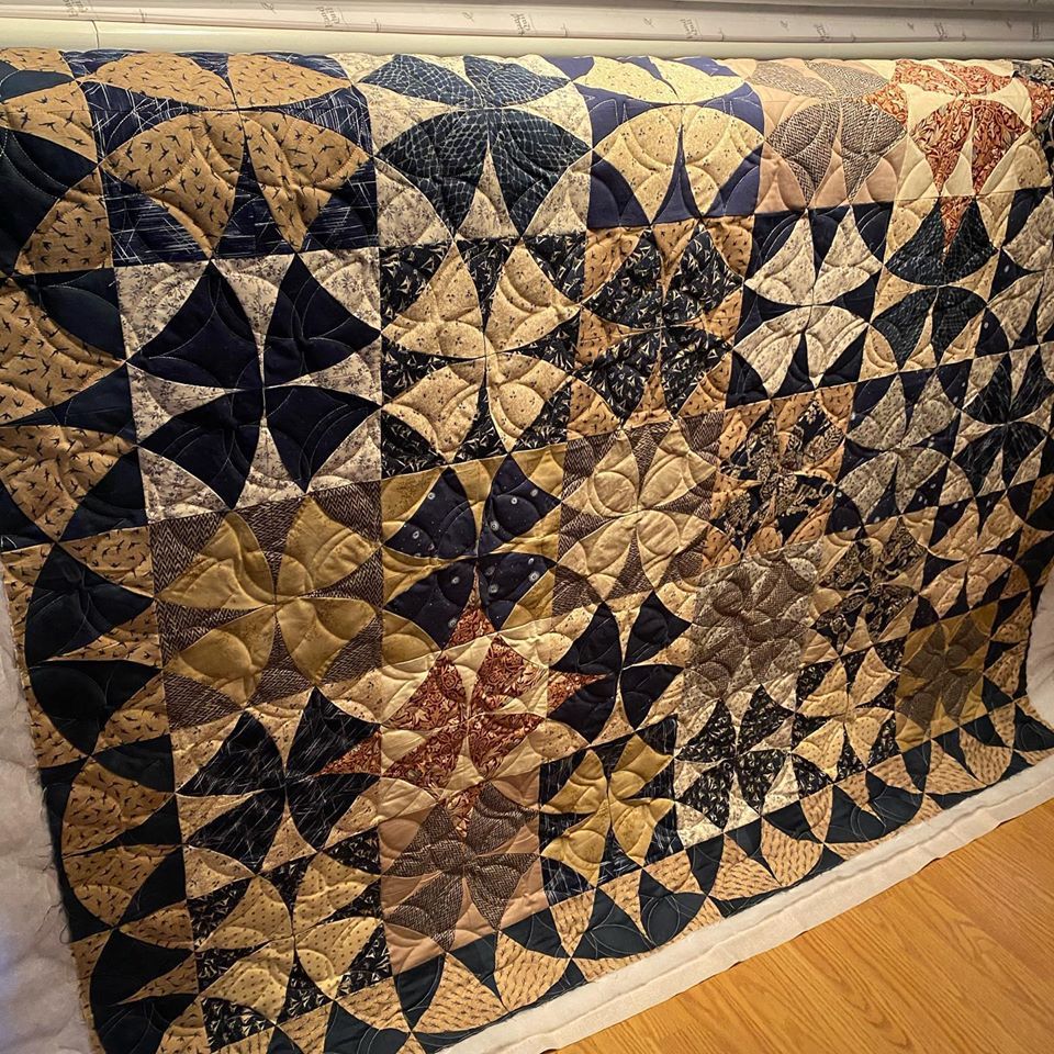 A quilt is hanging on a wall with a geometric pattern