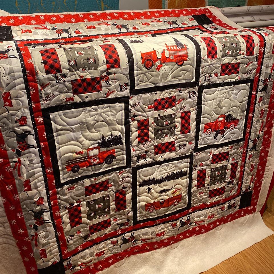 A quilt with a red truck on it is sitting on a table.