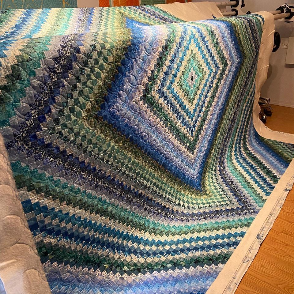 A blue and green quilt is sitting on a wooden table.