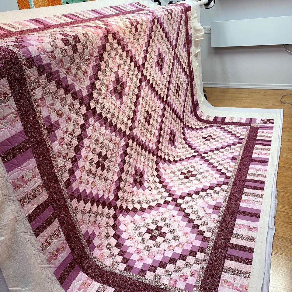 A pink and purple quilt is sitting on a wooden floor