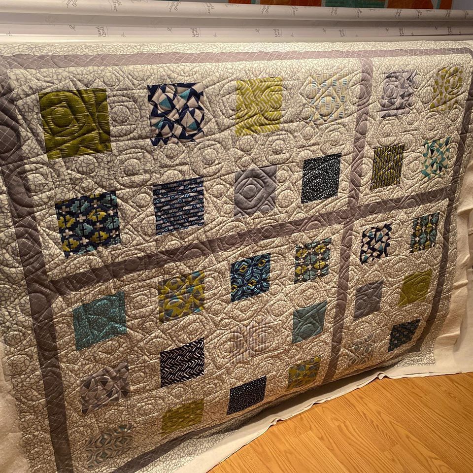 A quilt is sitting on top of a wooden table.