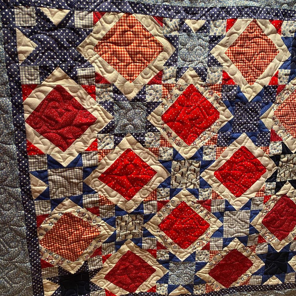 A close up of a quilt with red , white and blue squares