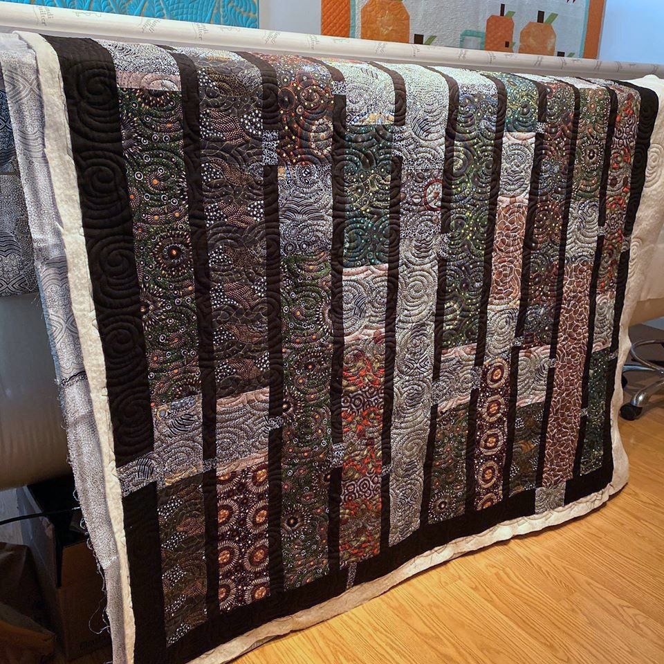 A colorful quilt is sitting on a wooden floor.