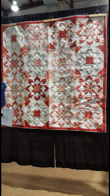 A large red and white quilt is hanging on a wall