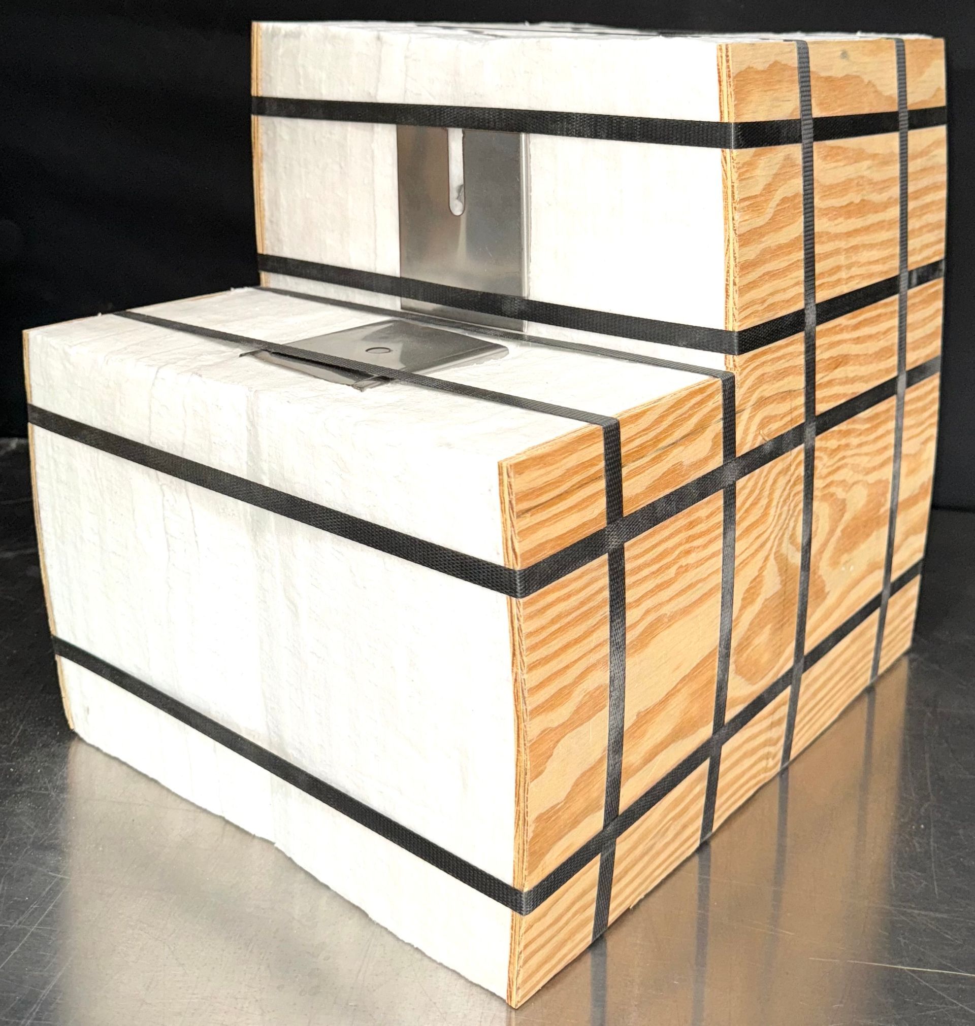 A wooden and fabric package is wrapped with black straps.