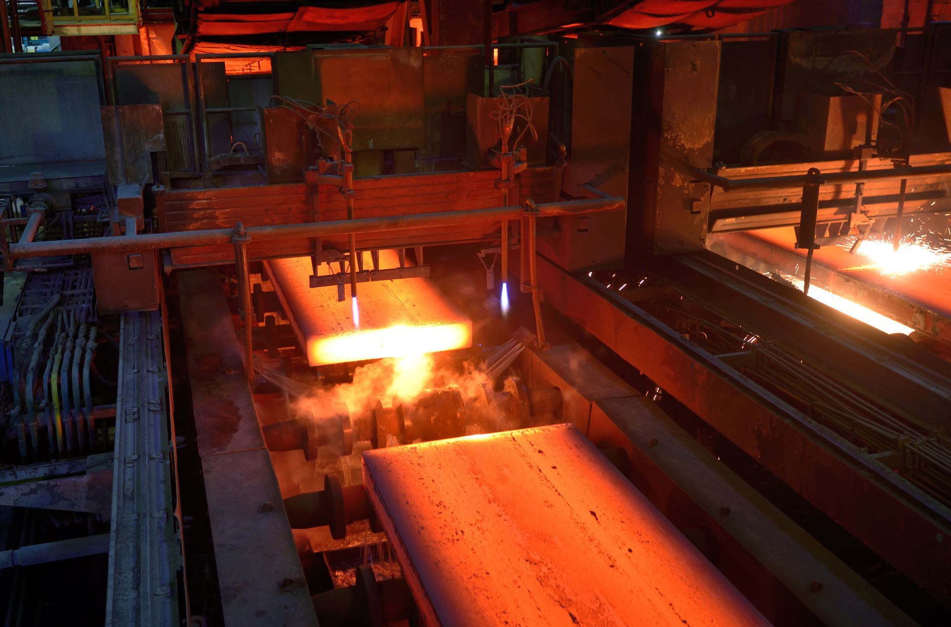 Molten metal pouring in an industrial factory with glowing orange machinery and conveyor lines