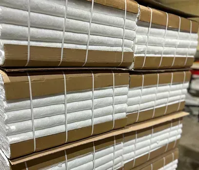 Stacks of wrapped white paper bound by brown cardboard and string.
